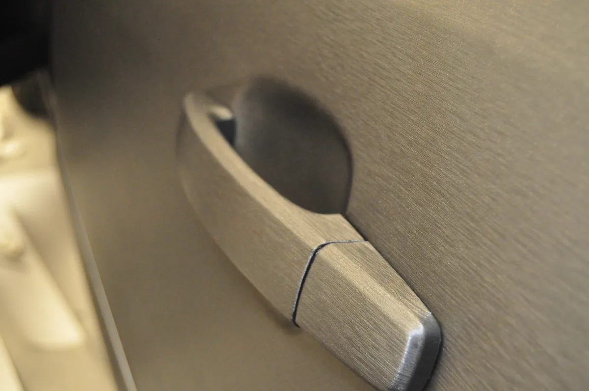 Detaliu mâner auto colantat evidențiind zona de cant și punctele sensibile unde pot apărea ridicări