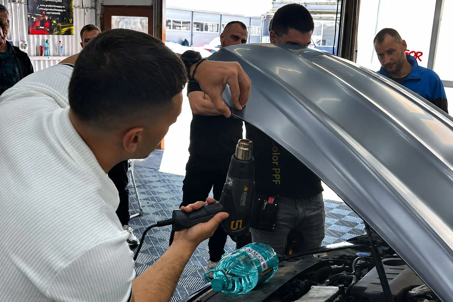 Aplicator auto folosind pistol cu aer cald la aplicarea PPF Carlas pe mașină, în cadrul unui workshop practic Verla Academy.