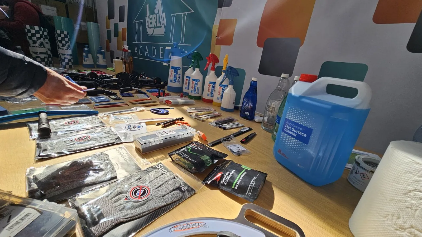 Accesorii profesionale pentru colantare auto prezentate la workshopul Verla: raclete, spray-uri, mănuși, cutter-e și soluții de curățare.