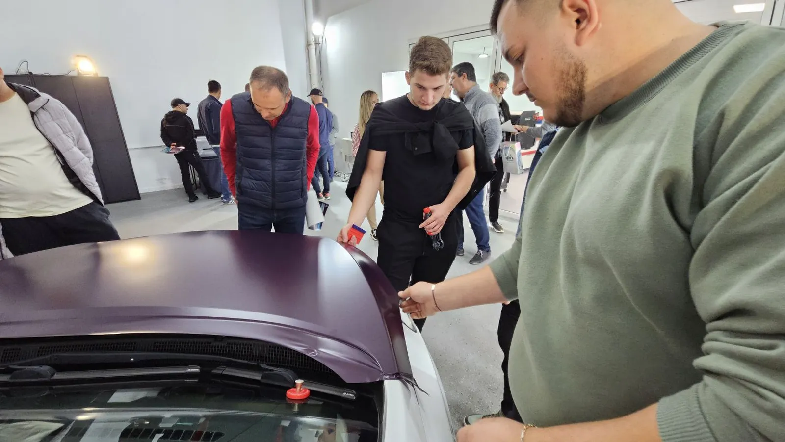 Cursanți analizând și exersând tehnici de aplicare folie auto în cadrul workshopului de colantări organizat de Verla.